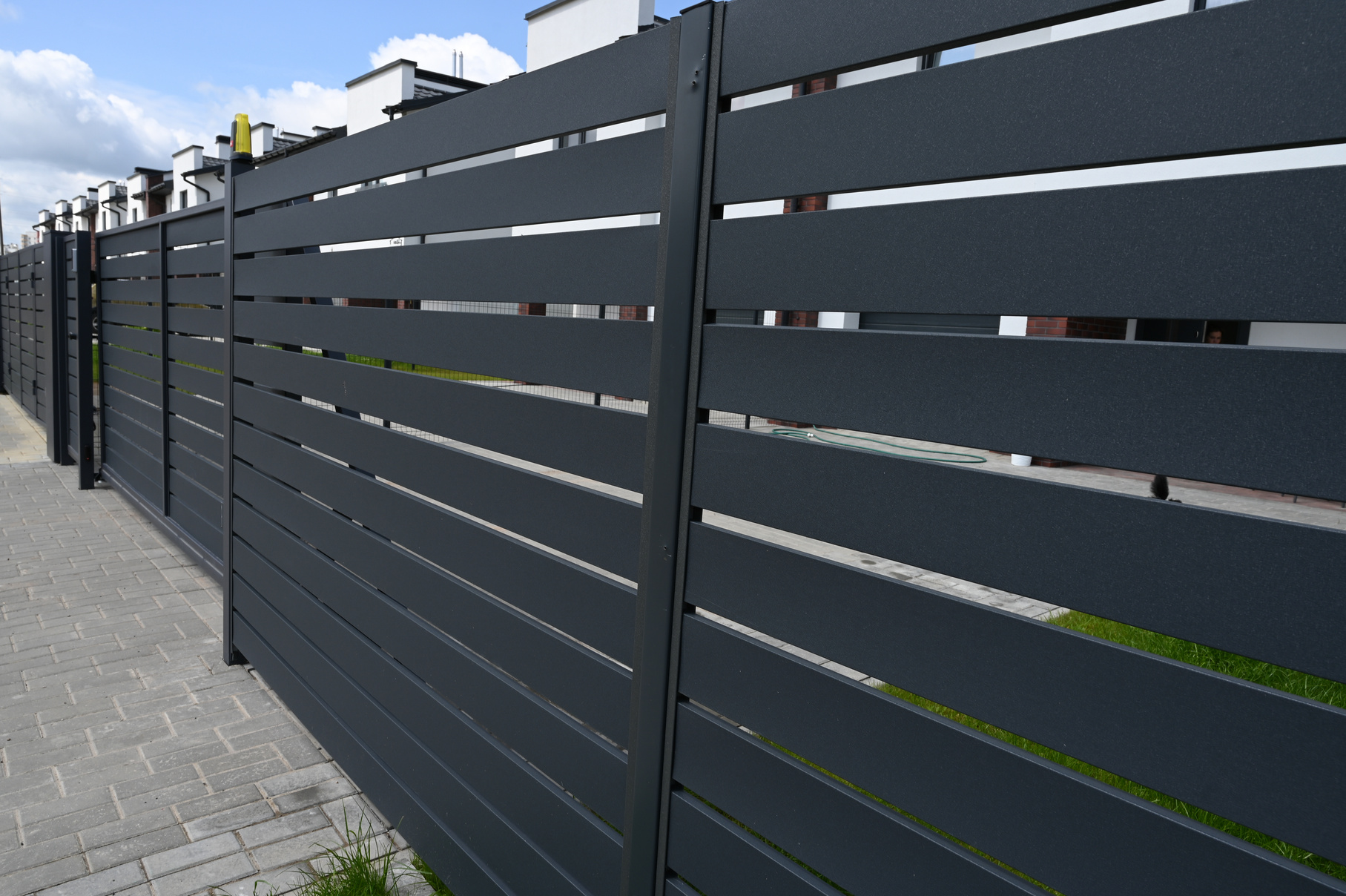 High grey fence. Modern barrier aluminum slats. Modern stone fence with metal shutters